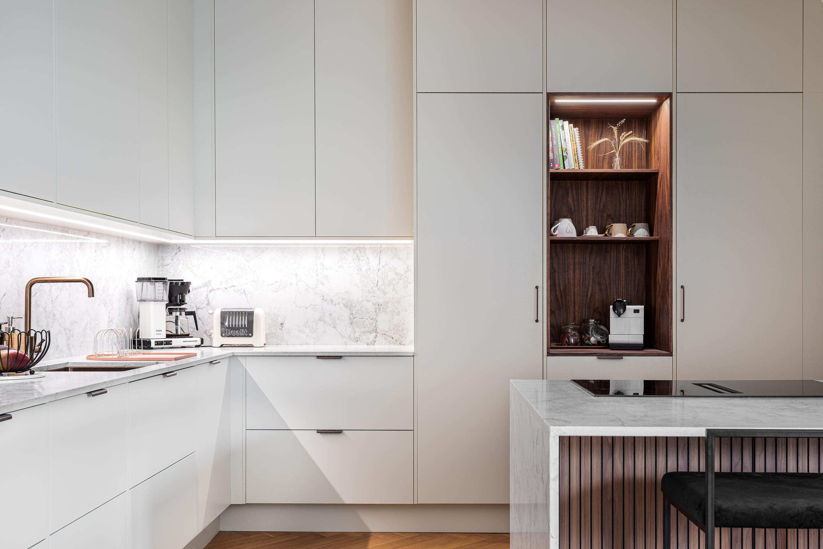 Grey kitchen with marble surfaces, brass details and a dark wood display niche. Grey kitchen with marble surfaces, brass details and a dark wood display niche.
