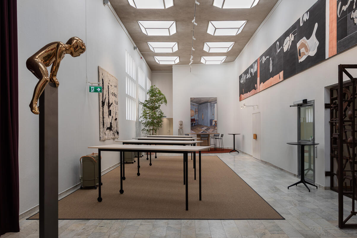 Architectural interior photography of Folksam headquarters in Stockholm, featuring a bright, high-ceilinged hall with contemporary artworks, including Maria Miesenberger’s golden sculpture “Leap of Faith (Getting Over)” and Eskil Eriksson’s textile artwork